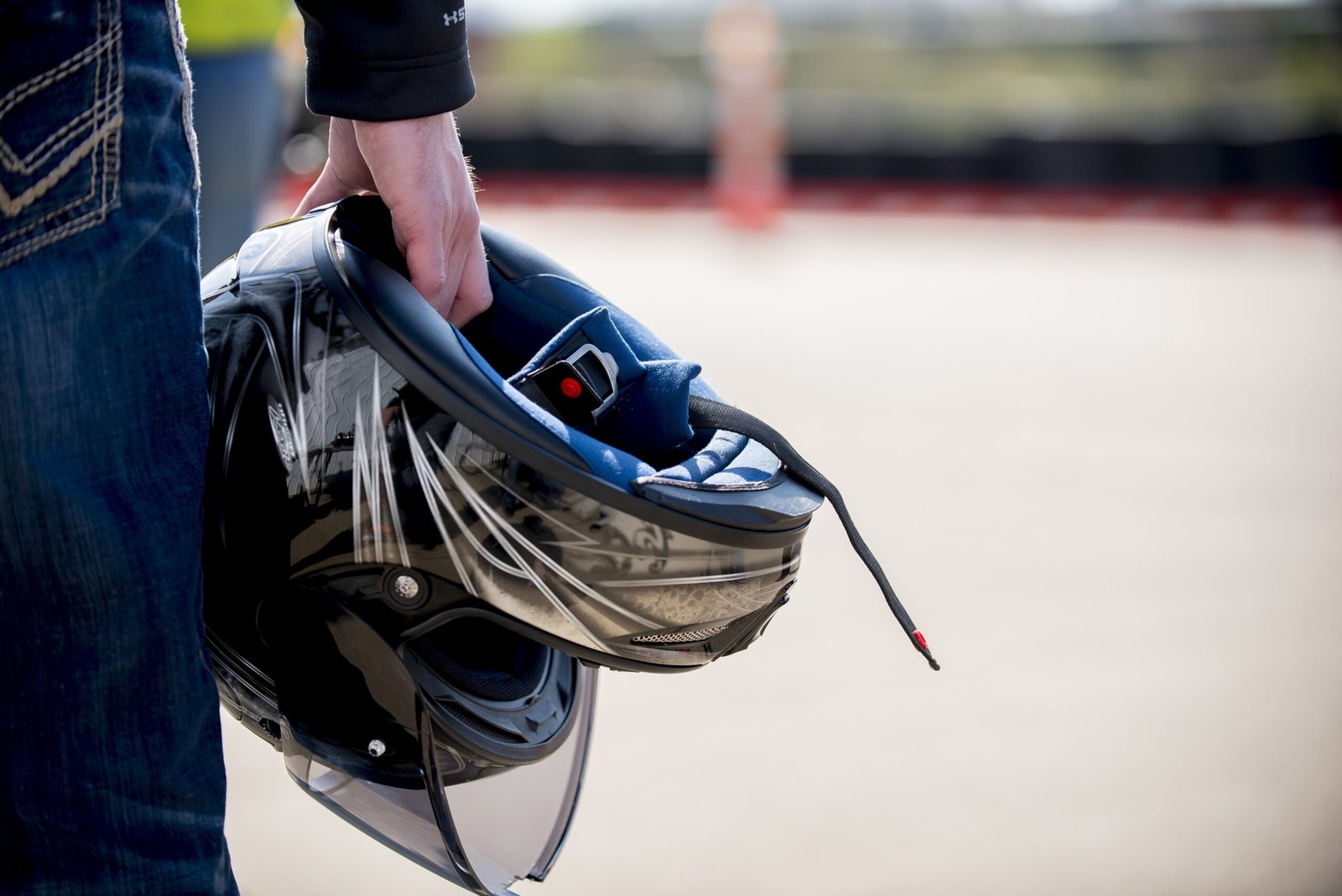 A closeup shot of a male holding his motorcycle helmet with a blurred background