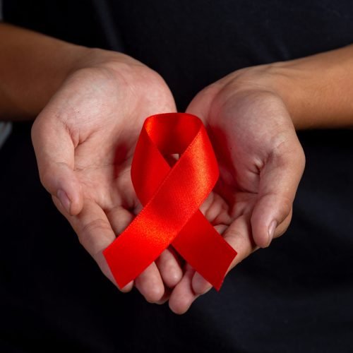 Woman hand holding red ribbon HIV awareness concept World AIDS Day and World Sexual Health Day.