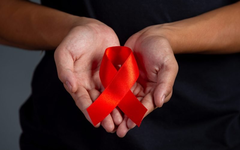 Woman hand holding red ribbon HIV awareness concept World AIDS Day and World Sexual Health Day.