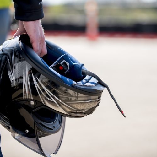 A closeup shot of a male holding his motorcycle helmet with a blurred background
