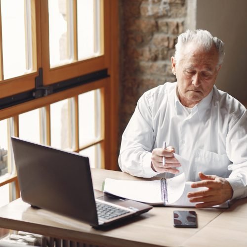 Senior with a laptop. Businessman working in the cafe. Man in a white shirt.